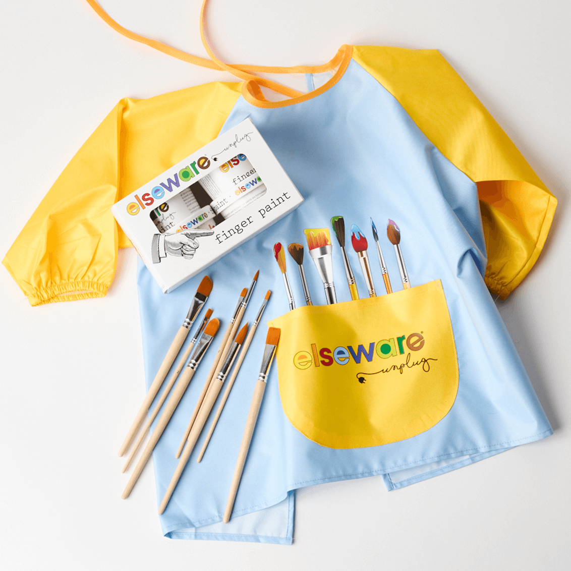 Yellow and blue smock with paintbrushes and finger paint set on a white background