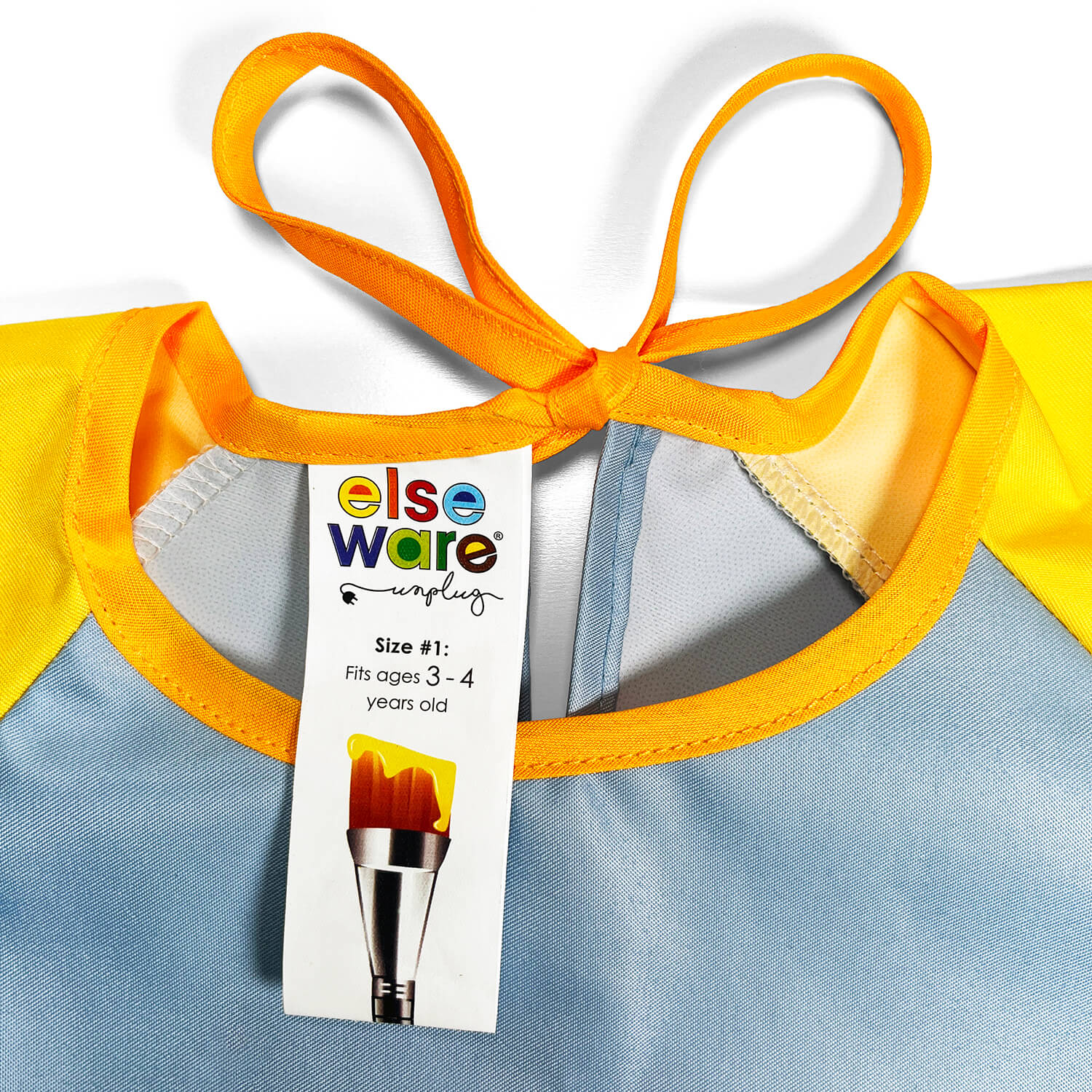 Children's elseware unplug smock with a yellow and blue design and a tag on a white background.