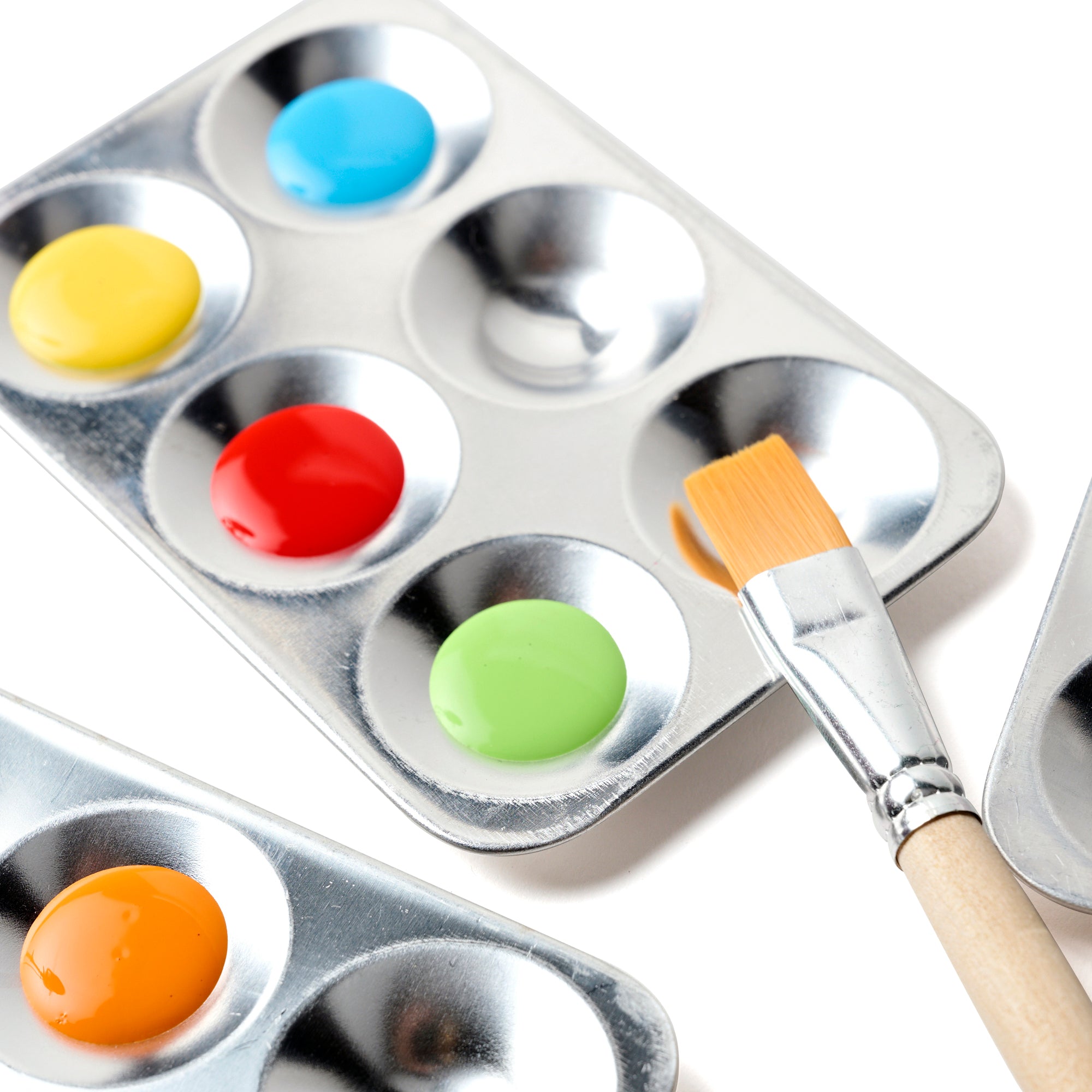 "Close-up of an Elseware Unplug aluminum paint palette filled with vibrant watercolor and acrylic paints in red, yellow, blue, green, and orange. A wooden-handled paintbrush rests beside the palette, making it perfect for blending and mixing colors in creative projects.