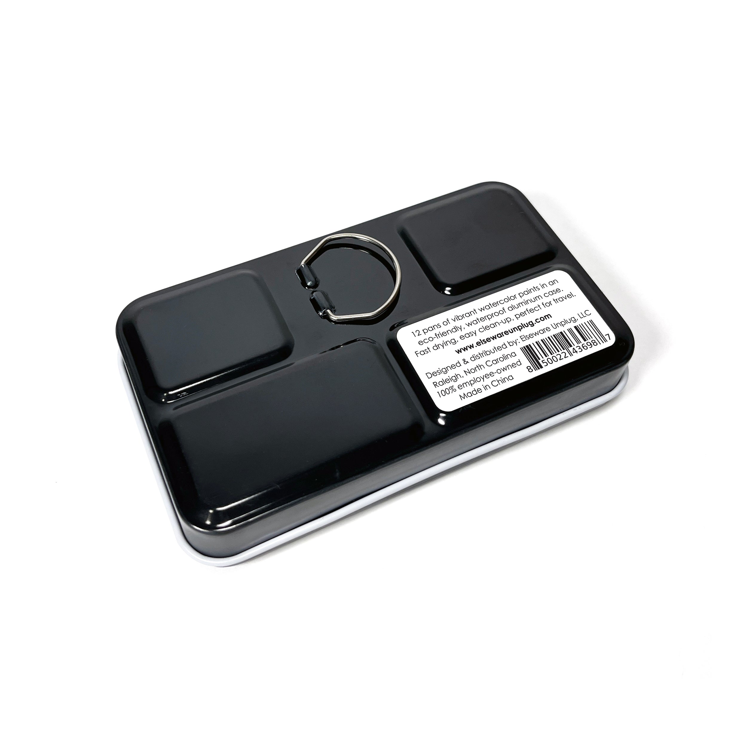 "Elseware Unplug Watercolor Set in a sleek, black aluminum travel case with a built-in ring for easy carrying. The back of the case features a label with product details, including a barcode, eco-friendly materials, and company information. Designed for portability, this compact watercolor kit is perfect for painting on the go.