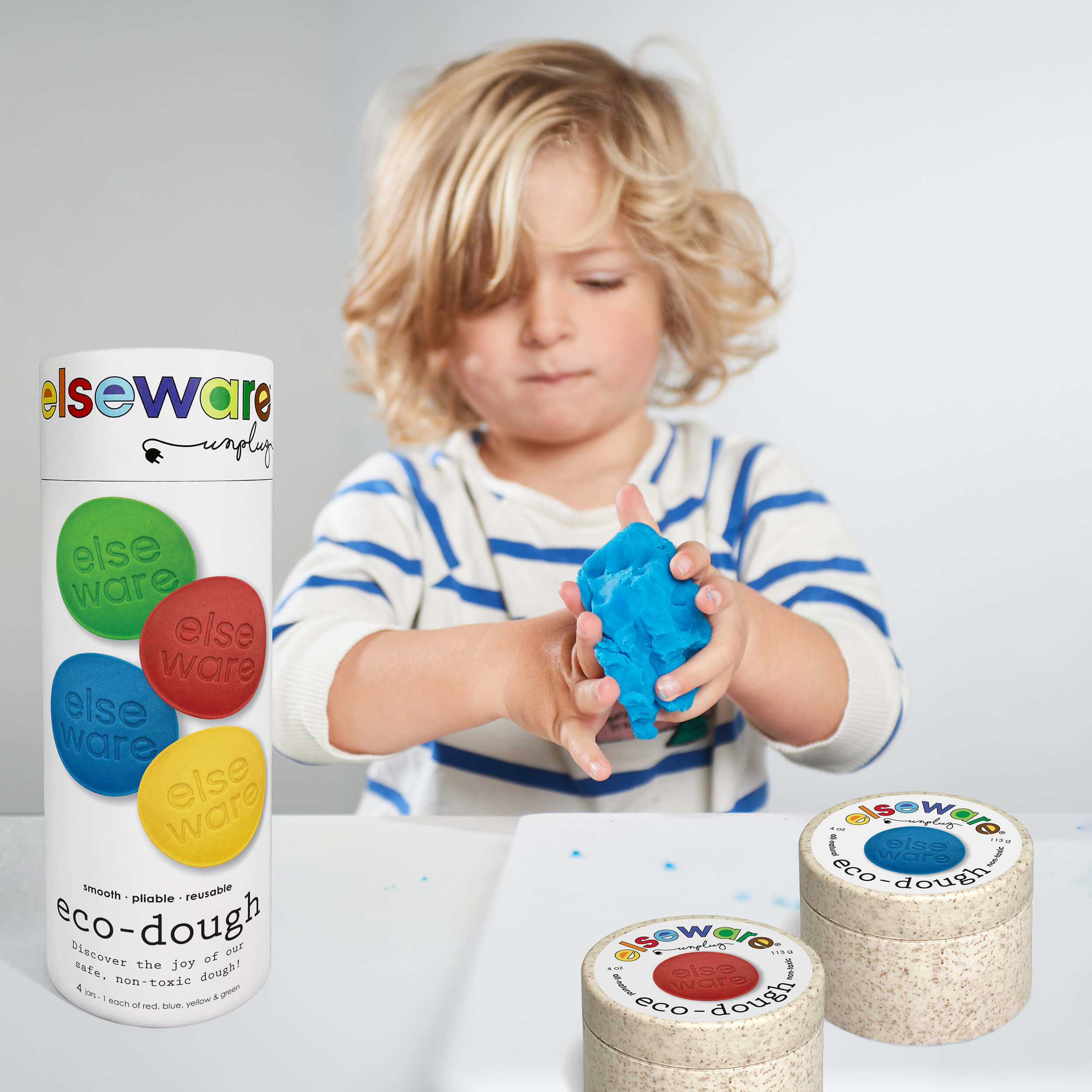 Child playing with eco-dough containers and a large container of elseware eco-dough.