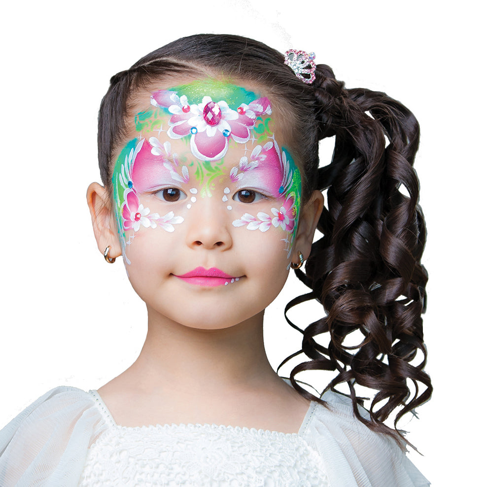 A young girl with long, curly brown hair styled in a high ponytail and a sparkling hair accessory wears an intricate floral face paint design created with Elseware Unplug’s eco-friendly face paints. The elegant design features soft pink and white flowers, green leafy details, and delicate white dots extending across her forehead and cheeks. A shimmering pink gemstone at the center completes the princess-like look. Elseware Unplug’s non-toxic, earth-friendly face paints provide safe, vibrant, and washable co