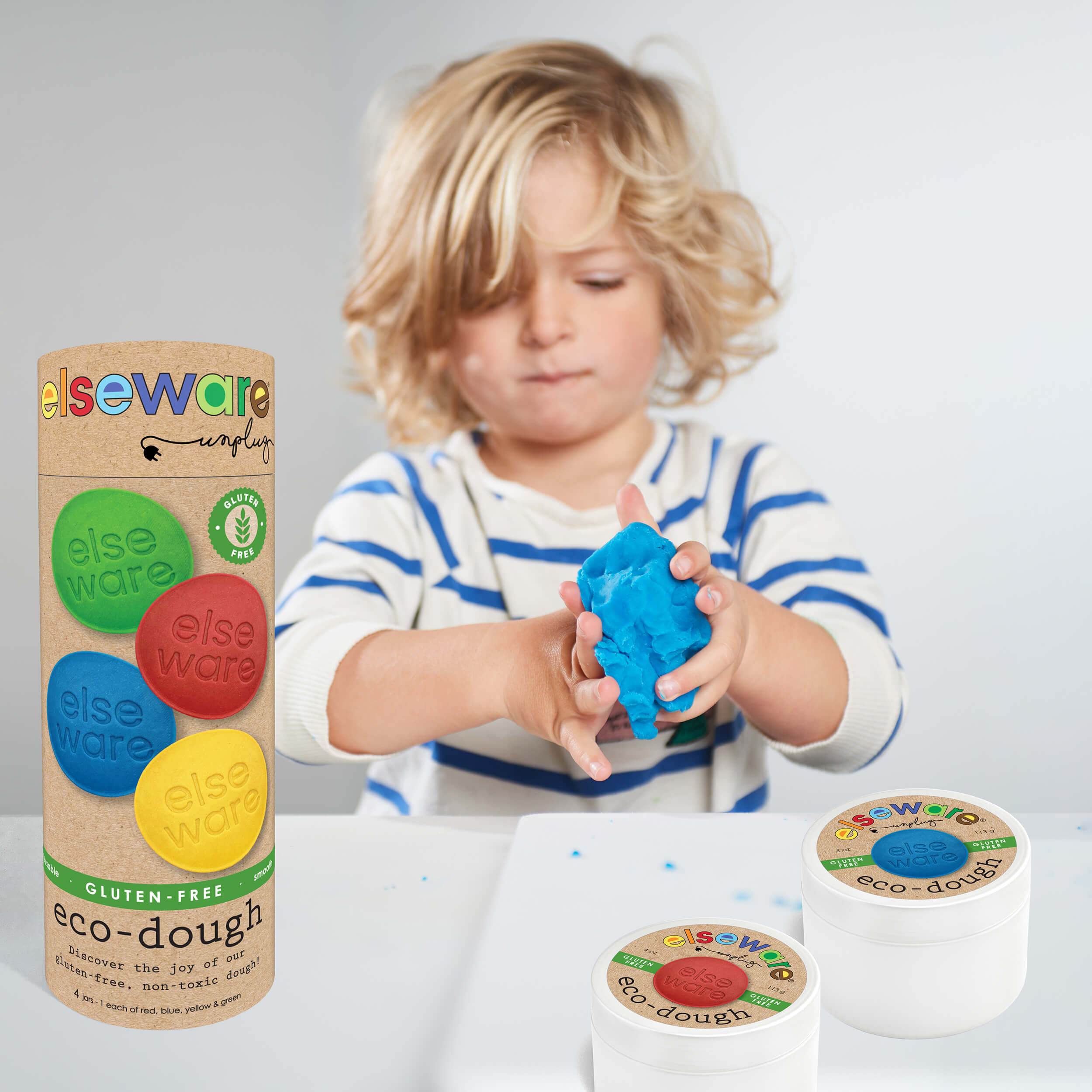 Child playing with bright blue eco-dough next to the Elseware Unplug gluten-free eco-dough tube and jars.