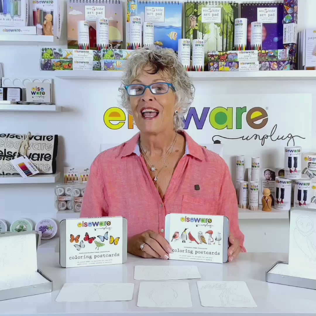 Product demo video showing coloring postcards on textured watercolor paper being decorated with watercolor paint, colored pencils, and markers, and stored in the reusable silver tin.