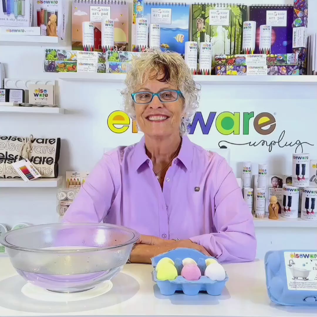 Product demo video showing an all natural lavender bath egg dropped into water where it fizzes and dissolves, releasing color and moisturizing oils into the bath.