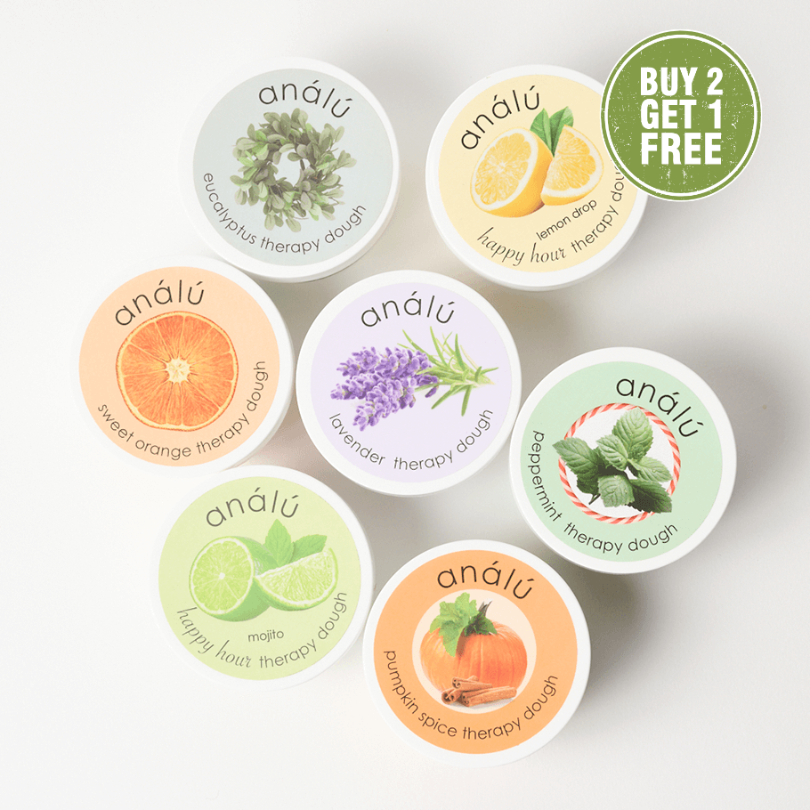 Collection of seven Analu Therapy Dough tins in assorted scents including Lavender, Peppermint, Sweet Orange, Lemon Drop, Mojito, Eucalyptus, and Pumpkin Spice, with a green ‘Buy 2 Get 1 Free’ label.